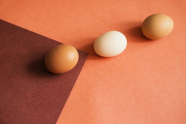 Three chicken eggs are laid on paper of natural colors. The texture of the paper and the egg is beige. Lines and triangles.Easter eggs.