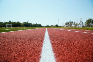 Koşu bandını yakın plan çekiyoruz. Spor sahasında beyaz çizgiler var. Spor temalı arka plan ve doku.