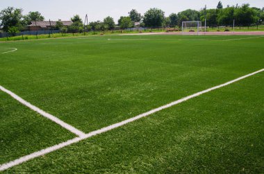 A green football field. A field of artificial grass in a school or public park. Sports ground for children and adults.