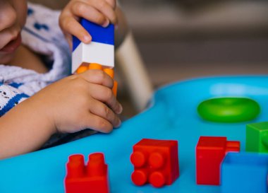 Çocuk çok renkli bir inşaatçı topluyor. Anaokulunda ya da evde çocuk dersleri. Çocukların gelişimi ve eğitimi.