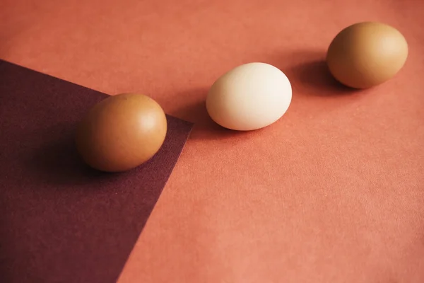 Three chicken eggs are laid on paper of natural colors. The texture of the paper and the egg is beige. Lines and triangles.Easter eggs.