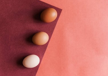 Üç tavuk yumurtası kağıdın doğal renklerine bırakılır. Kağıdın ve yumurtanın dokusu bej. Çizgiler ve üçgenler. Paskalya yumurtaları..