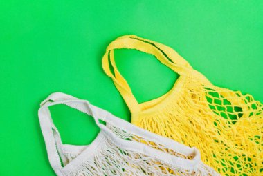 Plastiksiz sıfır atık kavramı. Yeşil zemin üzerinde tekrar kullanılabilen pamuklu ağ torbası. El yapımı. Doğayla ilgilenmek..