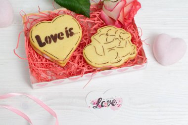 Kalp şeklinde kurabiyeler ve kırmızı gülle hediye paketi.