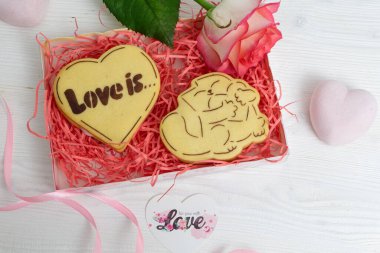 Kalp şeklinde kurabiyeler ve kırmızı gülle hediye paketi.