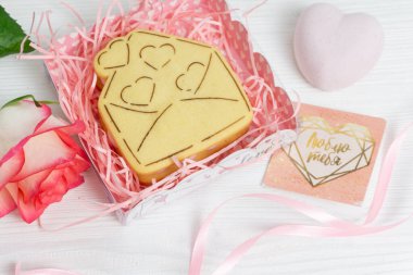 Kalp şeklinde kurabiyeler ve kırmızı gülle hediye paketi.