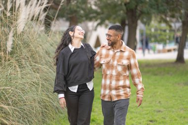 Güzel bir parkta kol kola yürüyen mutlu çift.