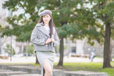 Açık havada duran modern kot elbiseli kendine güvenen bir kadının portresi.