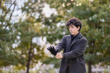 Yakışıklı kıvırcık saçlı adam dramatik bir şekilde deri eldivenlerini giyiyor.