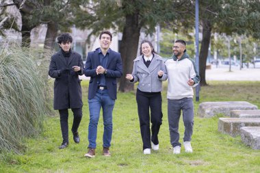 Çeşitli küçük insan grupları güzel bir doğal ortamda yürüyor ve gülüyor.