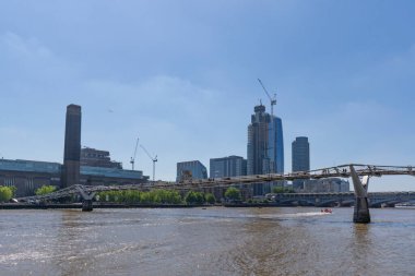 Londra, Birleşik Krallık - 16 Mayıs 2025: Arka planda şehir gökdelenleri ile Thames nehri boyunca uzanan modern Millennium Köprüsü yaya geçidi