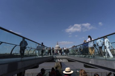 Londra, Birleşik Krallık - 16 Mayıs 2025: Milenyum Köprüsü 'nde Aziz Paul Katedrali' nin kubbesiyle birlikte yürüyen yayalar