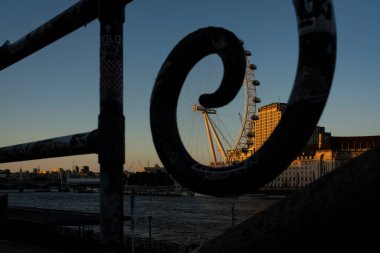 Londra, Birleşik Krallık - 17 Mayıs 2025: Londra Gözü süslü nehir kenarındaki korkuluklar tarafından çerçevelendi