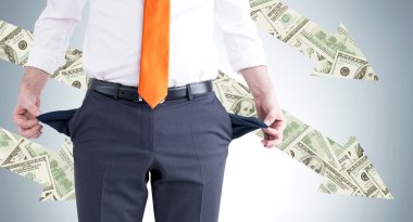 Turuncu kravatlı bir işadamı boş ceplerini ters çeviriyor. Ön görüş, kafa yok. Gri arka planda dolar okları. İflas kavramı.