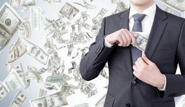 Göğüs cebine 100 dolarlık banknot koyan bir işadamı. Para arka planda uçuşuyor. Ön görüş, kafa yok. Para alma kavramı.