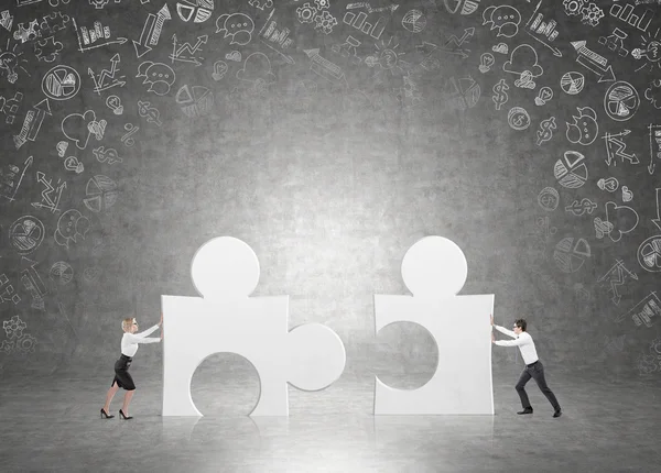 A man and a woman pushing matching puzzles to each other. — Stock Photo, Image