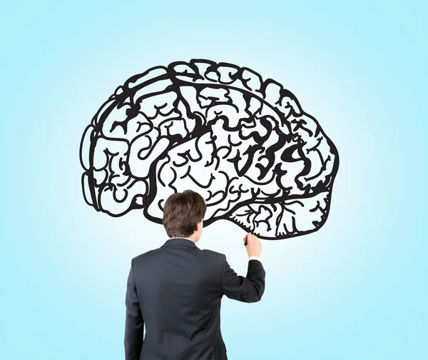 Empresario dibujando imagen del cerebro en la pared azul — Foto de Stock