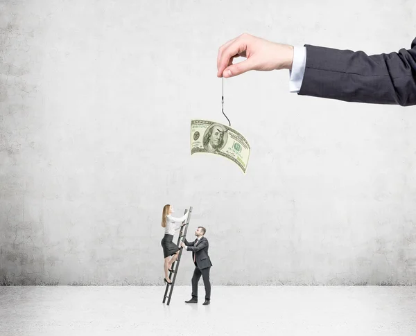 A hand holding a one-hundred dollar banknote on a thread, a young businesswoman climbing a ladder to get it, man assisting her. — Stock Photo, Image