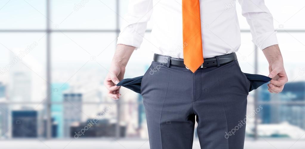 A businessman with an orange tie turning his empty pockets inside out.