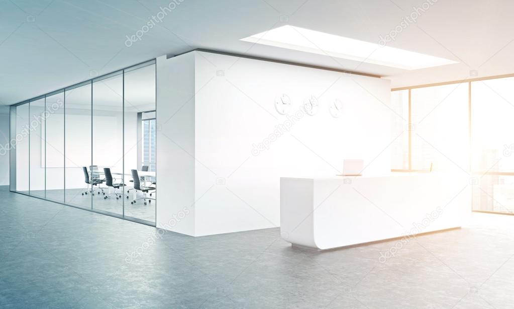 Empty office, white reception at white wall, three clocks on it.