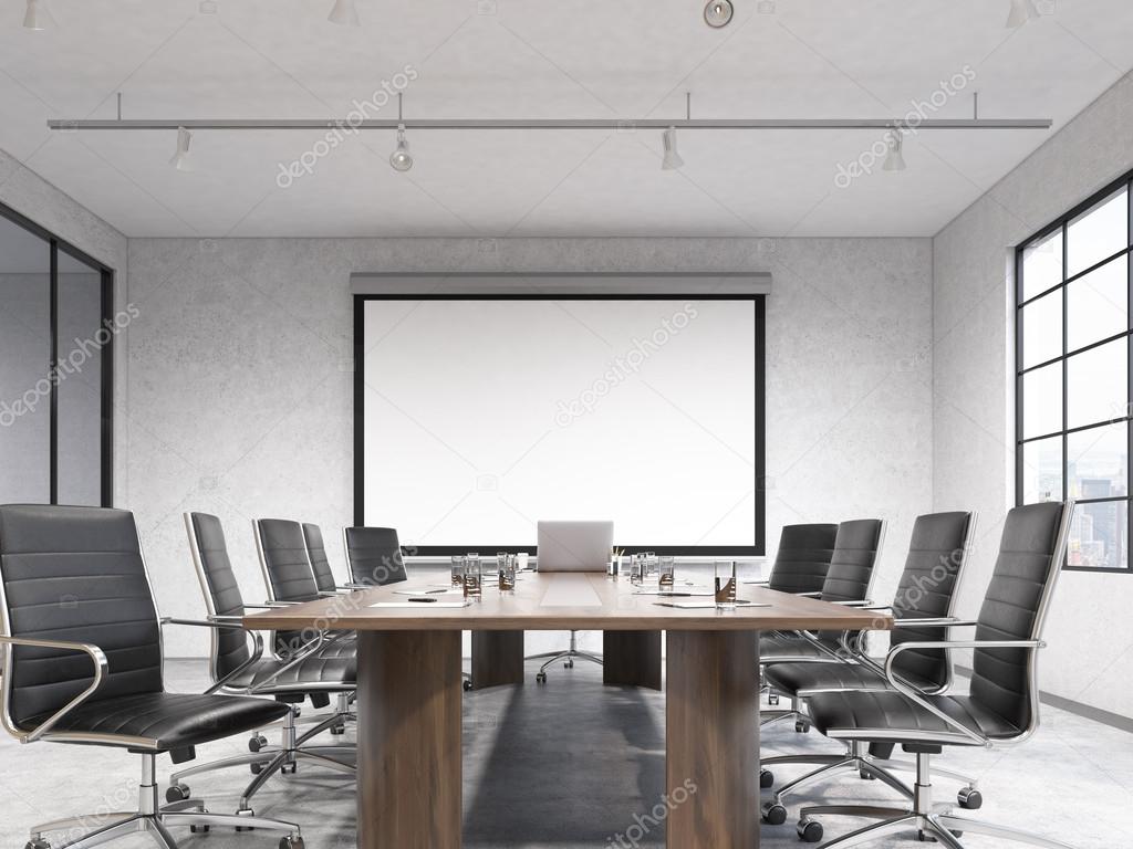 Big meeting room, blank poster on white wall behind table.