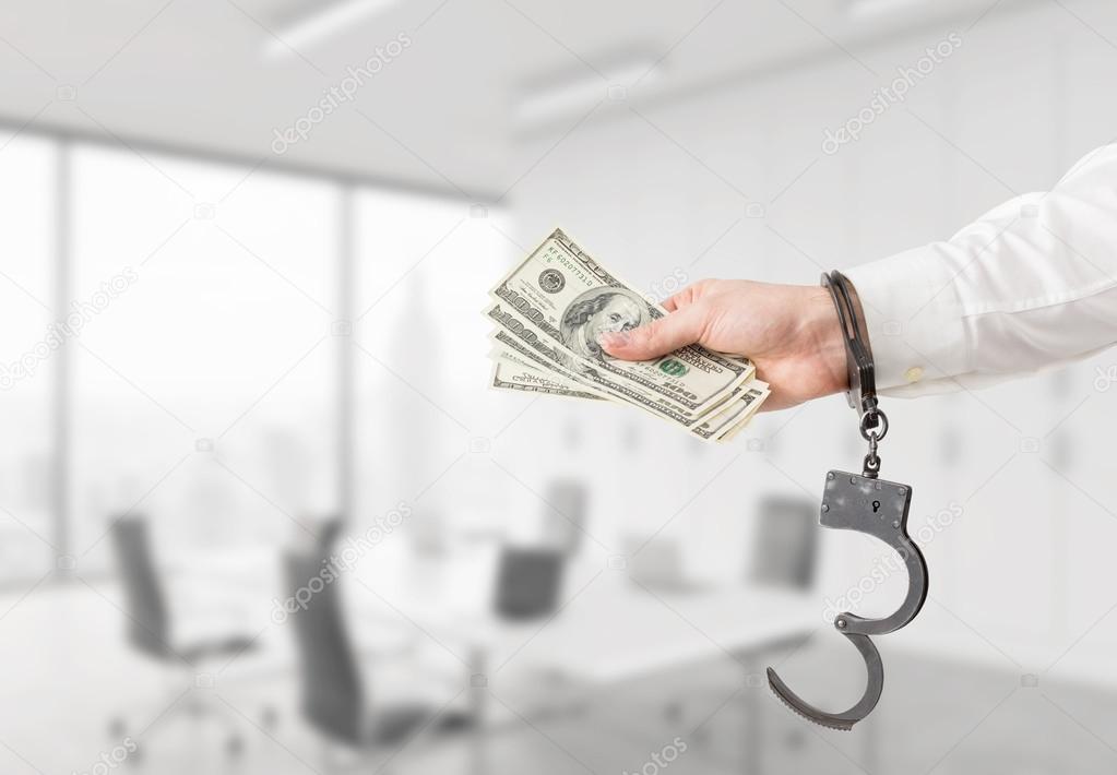 Hand with money in handcuffs