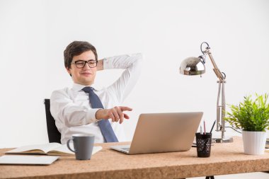 Smiling businessman in glasses in front of computer, pointing at screen.