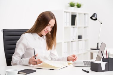 Notlar okuyan genç iş kadını gülümseyen. Office arka plan. İş kavramı.