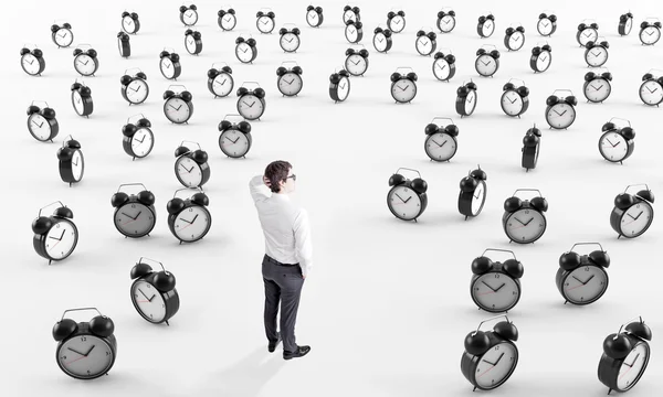 Businessman surrounded by alarm clocks — Stock Photo, Image