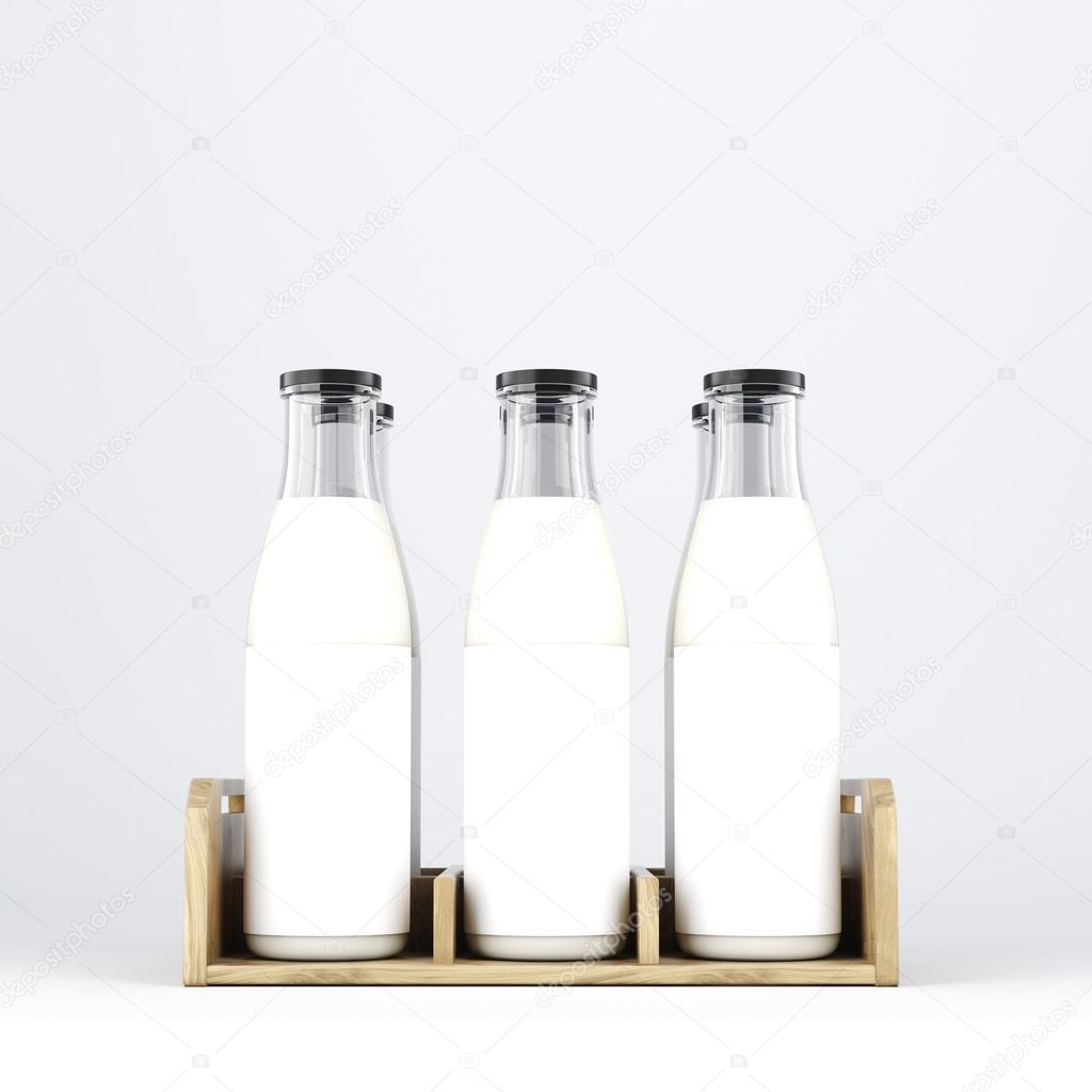 Six glass bottles of milk with black lids in wooden bottle box. Front view.