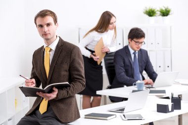 Kitapta not lar alan işadamı, arka planda işadamı ve iş kadını. Office. İş kavramı.