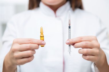 Doktor elinde şırınga ve koyu ampul, bulanık bir görünüm. Tıbbi yardım kavramı.