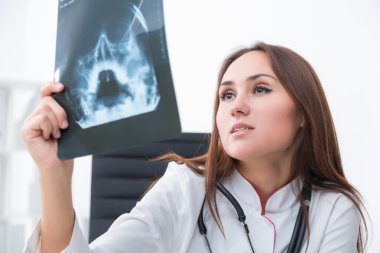 Kadın doktor röntgene bakıyor. Açık arka plan. İş kavramı.