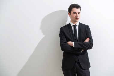 Akıllı takım elbiseli işadamı, elleri çapraz. Beyaz arka plan, gölge. İş modası kavramı.