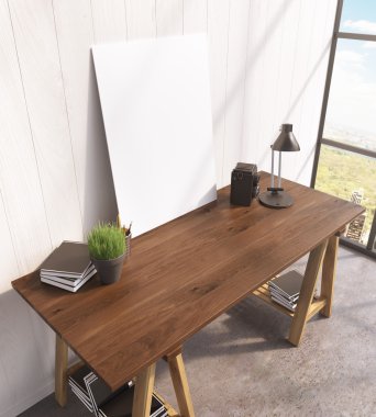 Blank frame on wooden table, books on and under table, lamp, window to the right.