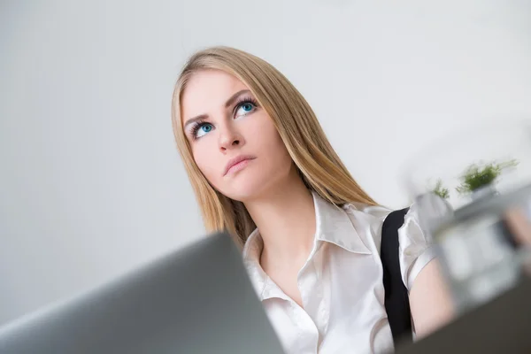 Blonde businesswoman in front of laptop. View from under table. Office at background. — Stock Photo, Image