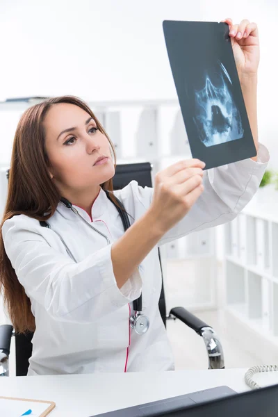 Female doctor looking at X-rays. Office at background. Concept of work. — Stock Photo, Image