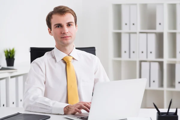 Businessman sitting at computer and looking in front, office at background. Concept of work. — Stock Photo, Image