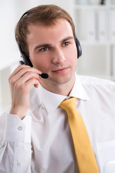 Lächelnder Geschäftsmann mit Kopfhörer, Mikrofon zur Seite, Büro. Konzept der Kommunikation. — Stockfoto