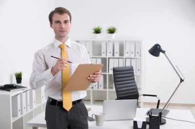 Not defteri olan bir işadamı ofiste duruyor. Ön görüş. İş kavramı.