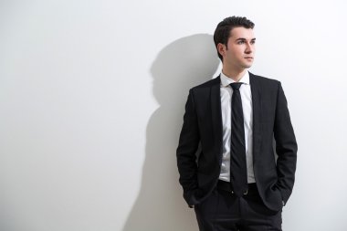 Akıllı takım elbiseli işadamı, elleri cepte. Beyaz arka plan, gölge. İş modası kavramı.