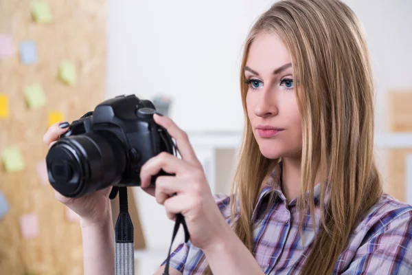 Mujer con ropa casual sosteniendo cámara fotográfica. Oficina en segundo plano. Concepto de trabajo . — Foto de Stock