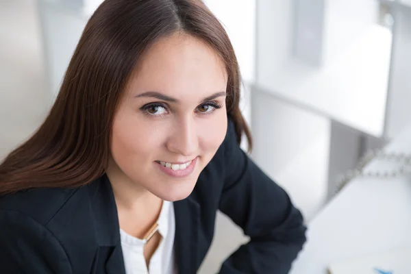 Una donna d'affari sorridente seduta a tavola e che guarda in alto. Ritratto. In ufficio. Concetto di lavoro . — Foto Stock