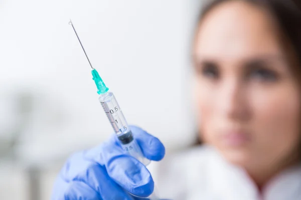 Doctor with hand in medical glove holding syringe, blurred look. Concept of medical help.