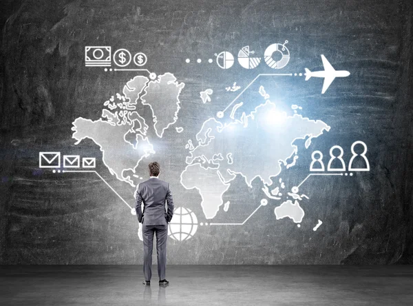 Empresário em pé na frente do mapa desenhado em quadro-negro, dinheiro, pessoas e pontos de comunicaçãoe avião sobre ele. Conceito de logística de negócios . — Fotografia de Stock