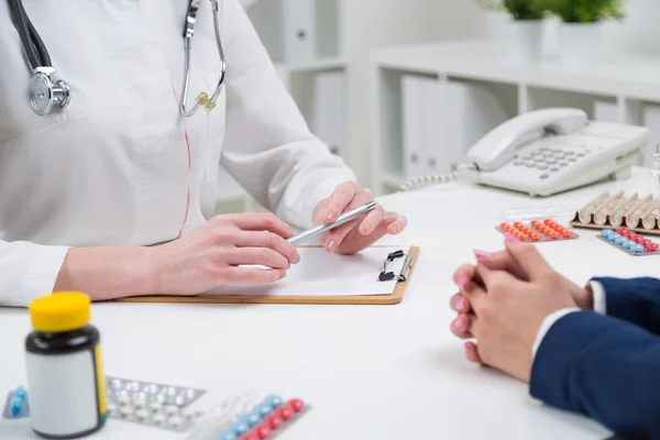 Arzt hört Patient zu und hält Stift in der Hand. Nur Hände gesehen. Tabletten auf den Tisch. Konzept der ärztlichen Beratung. — Stockfoto