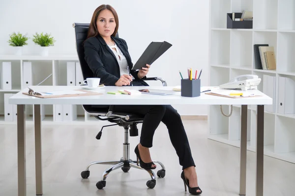 Businesswoman in suit with notebook sitting at table, tablet and coffee on it. Concept of work. — Stock Photo, Image