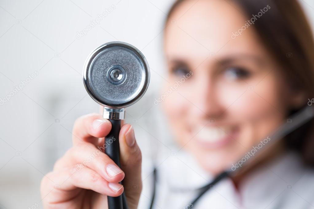 Улыбающийся доктор держит фонендоскоп, размытый взгляд. Концепция ...