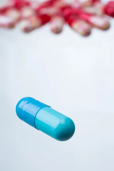Blå pillret, många liknande röda piller på bakgrunden. På nära håll. Begreppet medicin. — Stockfoto