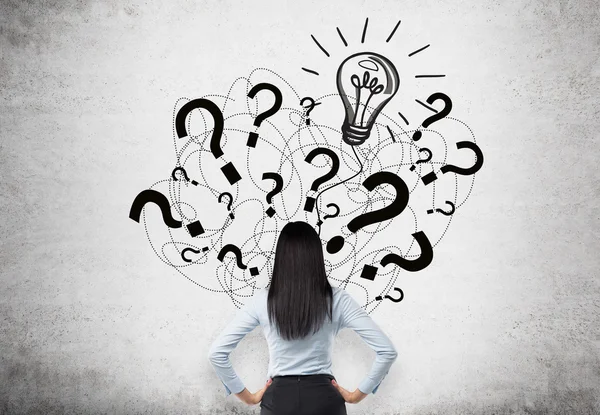 Idea concept with businesswoman facing question mark and bulb sketch on concrete wall — Stock Photo, Image